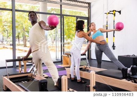 Positive woman and African-American man maintaining active lifestyle exercising with small pilates ball 110936483
