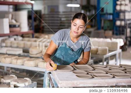 Female ceramist wiping clay bowl with sponge in ceramic factory 110936496