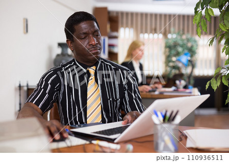 Focused african american man working at office desk Focused african american man working at office desk 110936511