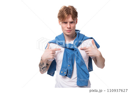 portrait of a young pensive european man with red hair and a tattoo on his arms on a studio 110937627