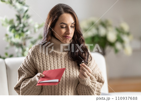 A young woman received a love letter from her boyfriend with an engagement ring, but she looks at it with embarrassment A young woman received a love letter from her boyfriend with an engagement ring, but she looks at it with embarrassment 110937688