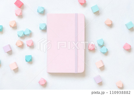 Pink hardcover notebook near pastel geometric decor on white table top view, textbook mockup 110938882