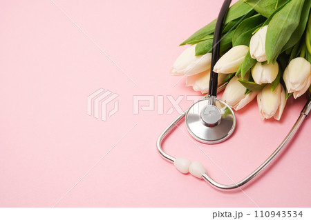 Bunch of white tulips with stethoscope on pink background. National Doctor's day. Happy nurse day. Top view with copy space Bunch of white tulips with stethoscope on pink background. National Doctor's day. Happy nurse day. Top view with copy space 110943534