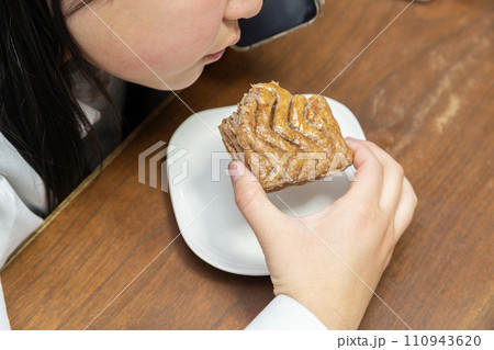 電話をしながらおやつを食べる中学生 110943620