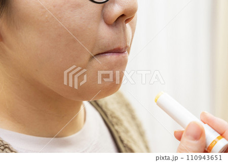 唇にリップクリームを塗る女性 唇にリップクリームを塗る女性 110943651