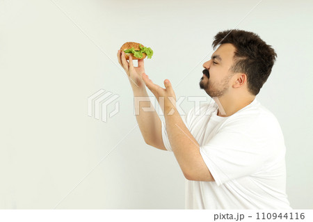 A fat man with a hamburger, on a gray background. 110944116