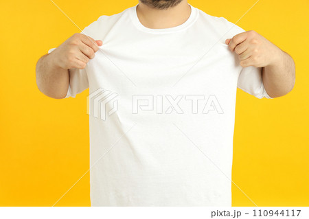 A man with a blank white t-shirt, on a yellow background. 110944117