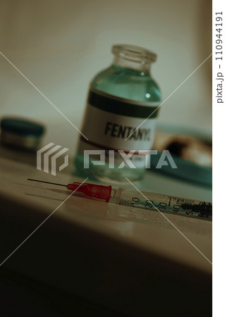 open vial of fentanyl and syringe on sordid toilet 110944191