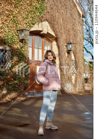 Young beautiful pretty tourist girl in warm hat and coat with backpack walking at cold autumn in Europe city enjoying her travel in Bietigheim-Bissingen, Deutschland. Outdoor portrait of young tourist 110944644