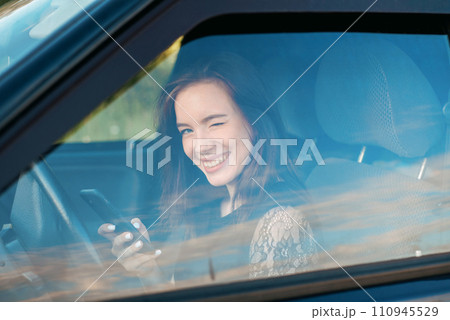 a girl driving a car chats on the phone. pretty young girl driving 110945529
