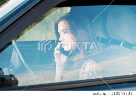 a girl driving a car chats on the phone. pretty young girl driving a girl driving a car chats on the phone. pretty young girl driving 110945535