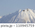 厳冬の大山をバックに飛翔するカモ 110945759
