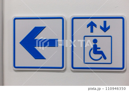 A blue arrow and elevator access signs disabled person on the wall 110946350