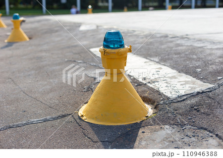 Close-up of a yellow runway marker with a blue light, indicating directions on the airport tarmac 110946388
