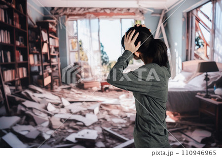 地震で家が倒壊して途方に暮れる女性 110946965