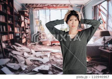 地震で家が倒壊して途方に暮れる女性 110946967