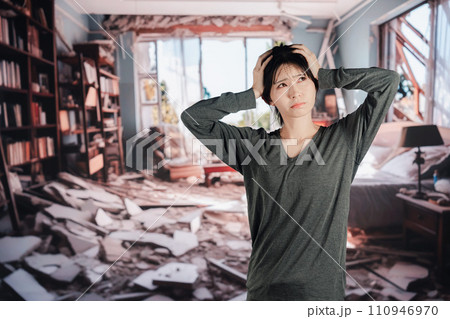 地震で家が倒壊して途方に暮れる女性 110946970