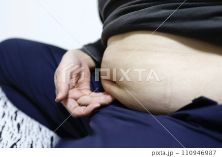 座っている中年男性のお腹の脂肪 110946987
