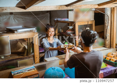 Asian woman selling giving a plate of food to buyer Asian woman selling giving a plate of food to buyer 110947257