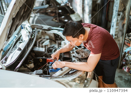 A male mechanic checks a car battery at a service station 110947394