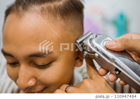 asian male customer getting hair cut in barbershop cropped view 110947484