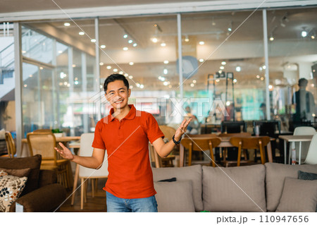 male shop assistant in red with an excited expression in furniture store male shop assistant in red with an excited expression in furniture store 110947656
