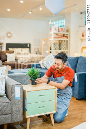 male shop assistant working on decorating a cupboard at a furniture store 110947772