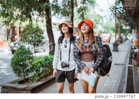 two backpacker girls search for tourist destinations with a road map two backpacker girls search for tourist destinations with a road map 110947787