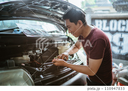 A mechanic opens the hood to check the radiator 110947833