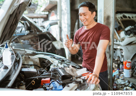 young male mechanic finds a solution to fixing machines in the workshop young male mechanic finds a solution to fixing machines in the workshop 110947855