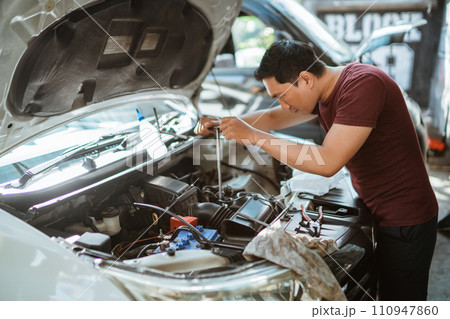 young male mechanic using tools to repair a car engine young male mechanic using tools to repair a car engine 110947860