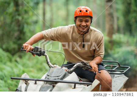 happy asian man smiling brightly while enjoy his atv trip happy asian man smiling brightly while enjoy his atv trip 110947861