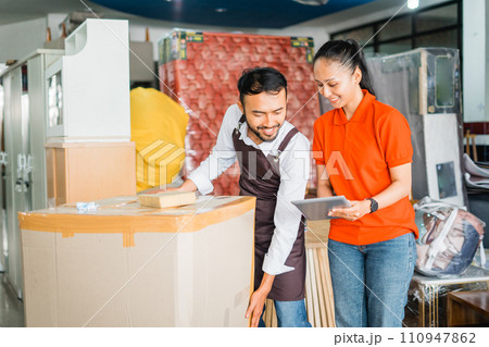 female and male shop assistants wrap consumer goods in cardboard boxes female and male shop assistants wrap consumer goods in cardboard boxes 110947862