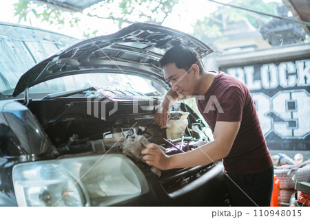 A mechanic opens the hood to repair a car engine 110948015