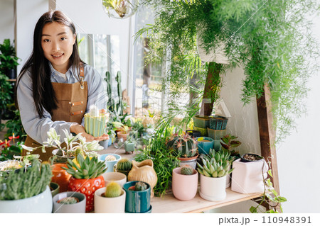 Small business, home decor concept. Professional young Asian female floral store owner arranges flower pots, takes stock daily routine of running a small business. Small business concept. Small business, home decor concept. Professional young Asian female floral store owner arranges flower pots, takes stock daily routine of running a small business. Small business concept. 110948391
