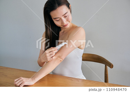 電気シェーバーで腕毛を剃る30代女性 110948470