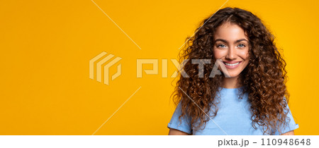 Smiling curly-haired woman on yellow background, panorama, copy space 110948648