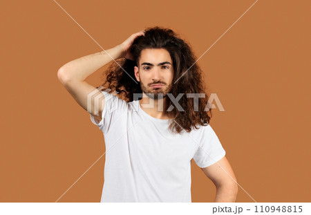 man with long hair looking puzzled against beige backdrop man with long hair looking puzzled against beige backdrop 110948815