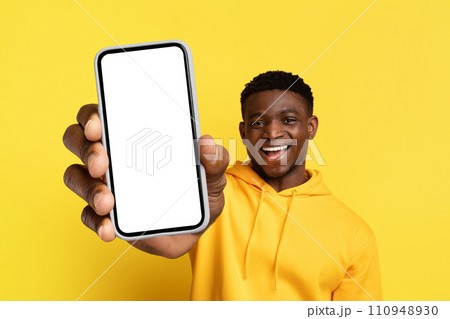Happy young black guy showing big phone with blank screen Happy young black guy showing big phone with blank screen 110948930