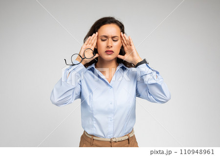 Despaired millennial caucasian lady, with pained expression, clutching at temples Despaired millennial caucasian lady, with pained expression, clutching at temples 110948961