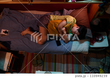 Girl with pillow sleeping on single bed 110949239