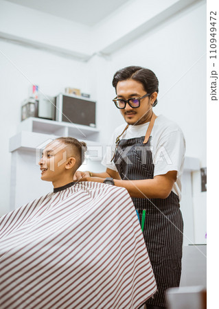 asian male barber putting a cape on his customer 110949472