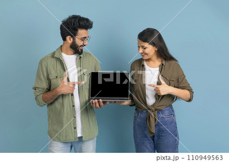 Loving eastern couple showing laptop with black empty screen 110949563