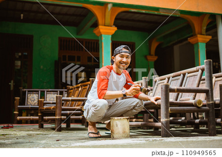 Asian bamboo craftsman smiles at the camera while polishing 110949565