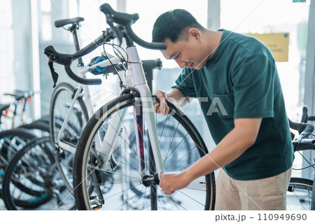 young Asian man installs bicycle tires while working on assembling bicycles 110949690