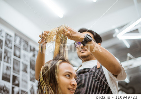 asian male hairdresser cutting his customer hair asian male hairdresser cutting his customer hair 110949723