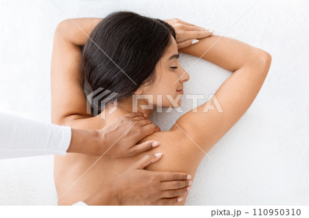 Beautiful naked woman getting relaxing back massage, view above Beautiful naked woman getting relaxing back massage, view above 110950310