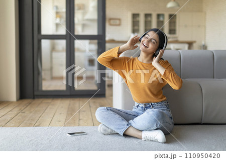 Favorite Song. Smiling Indian Woman Wearing Wireless Headphones Listening Music At Home Favorite Song. Smiling Indian Woman Wearing Wireless Headphones Listening Music At Home 110950420