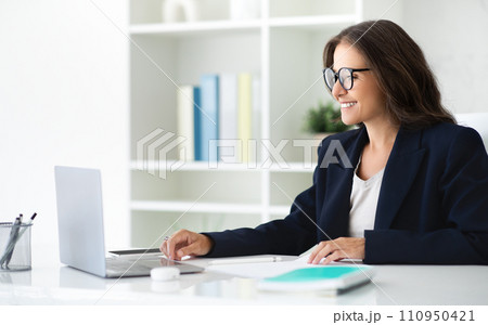 Positive mature woman manager using laptop at office 110950421