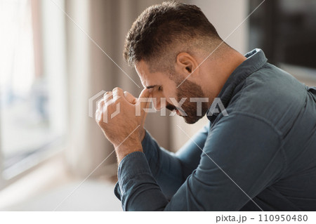 Depressed middle aged man grapples with grief sitting at home 110950480
